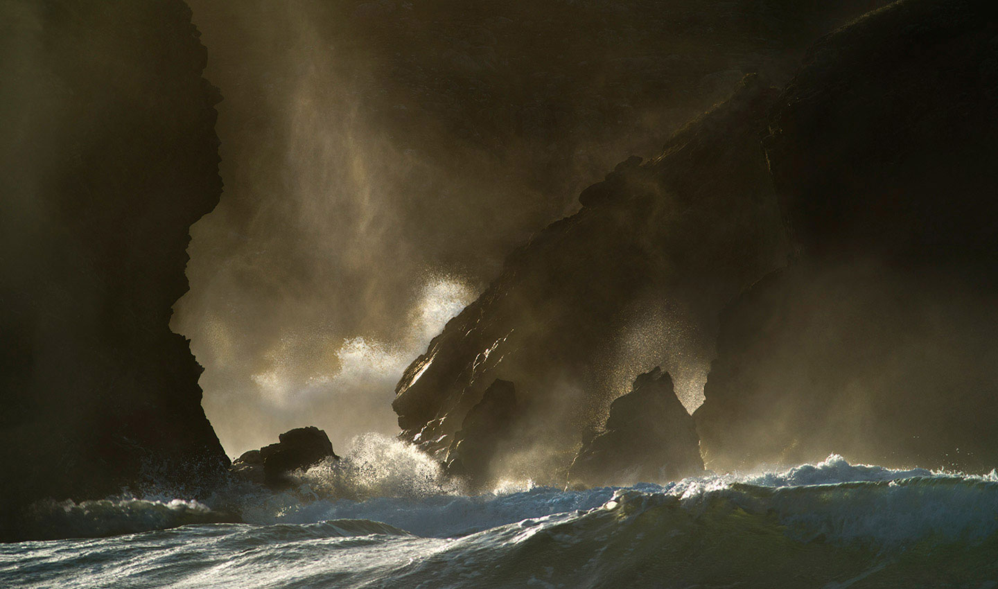 The raging seas smashing against the cliffs at Dailbeag on the Isle of Lewis, the mist rising from the rough seas are caught under the last vestiges of the fading sun.