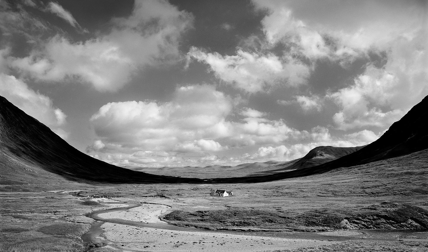 The massive expanse of Rannoch Moor, Glencoe, Scotland. This valley is punctuated by the shadow across the valley floor highlighting a lone cottage sitting in the vastness of the valley.
